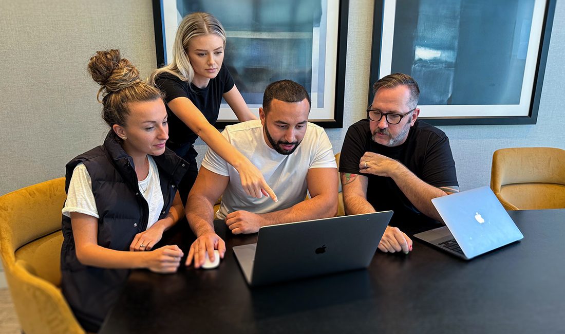 Trivium Employees surrounding computer in office